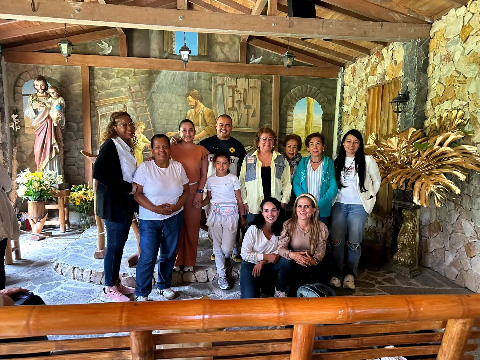Peregrinos en la capilla de la carpintería de San José, con el mural del santo trabajando la madera